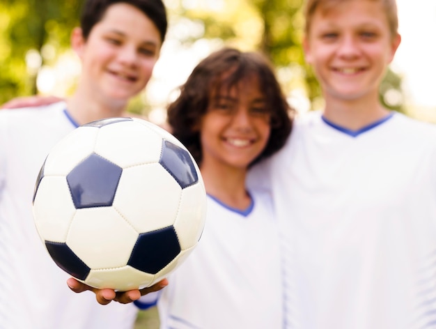 Chicos en ropa deportiva sosteniendo una pelota de fútbol.