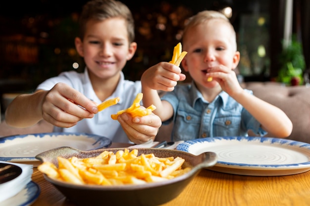 Chicos sonrientes de tiro medio comiendo papas fritas