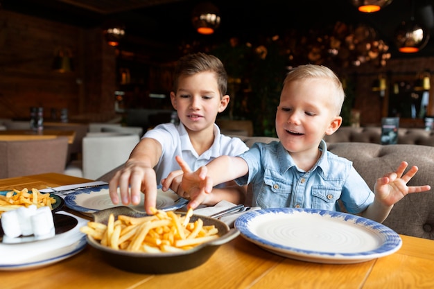 Chicos de tiro medio comiendo papas fritas