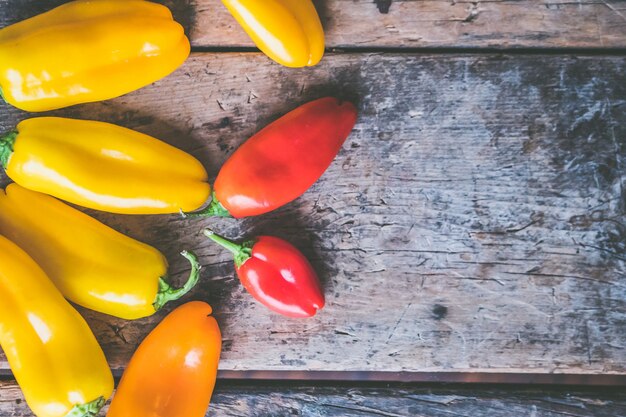 Foto gratuita chiles amarillos y rojos en un montón sobre una superficie de madera