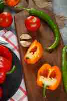 Foto gratuita chiles, pimientos amarillos, tomate y ajos en una tabla de madera. vista superior.
