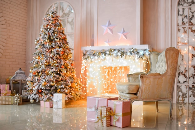 Chimenea blanca decorada con guirnalda amarilla y árbol de Navidad de pie por ella