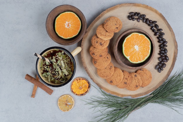 Chip cookies, granos y rodaja de mandarina sobre tabla de madera.