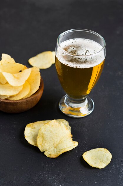 Chips de ángulo alto al lado del vaso con cerveza