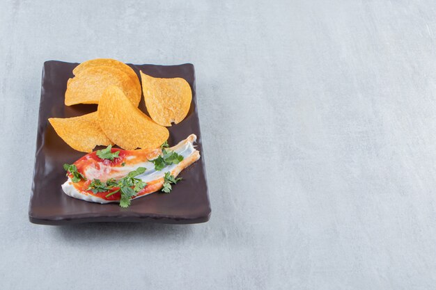 Chips crujientes junto con salsa de tomate y mayonesa en un plato oscuro.