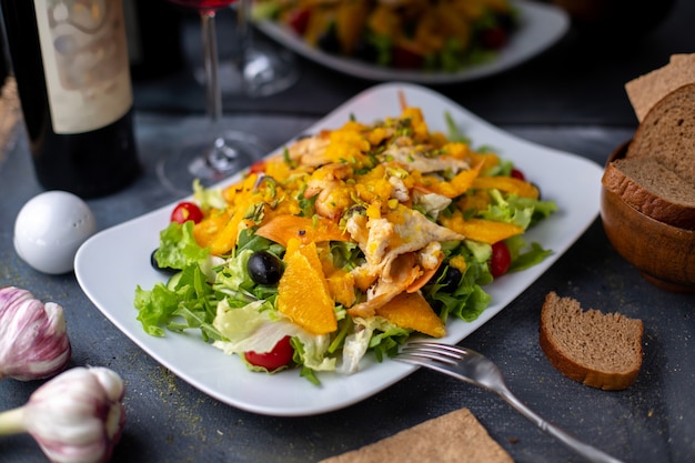 chips de ensalada de naranja con vegetales en rodajas junto con vino tinto en escritorio gris