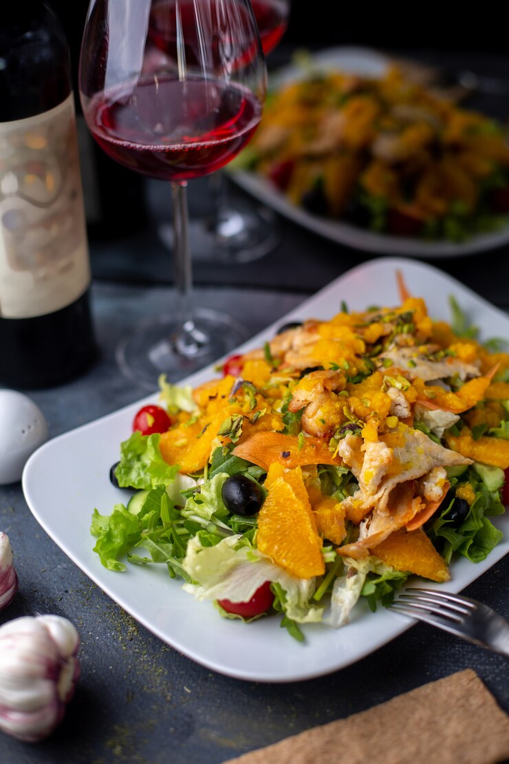 Foto gratuito chips de ensalada de naranja con vegetales en rodajas junto con vino tinto en escritorio gris