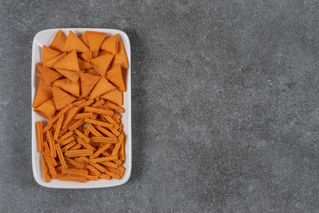 Chips de maíz y pan seco en un recipiente sobre la superficie de mármol