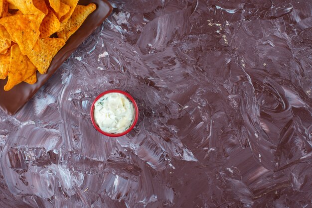 Chips picantes en un plato junto a un cuenco de mayonesa, sobre la mesa de mármol.