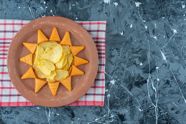 Chips de queso y chips de cono en un plato sobre un paño de cocina, sobre la mesa de mármol.