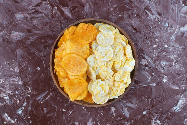 Chips de queso y patatas fritas en placa sobre mármol.