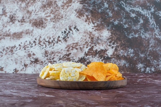 Chips de queso y patatas fritas en placa sobre la superficie de mármol