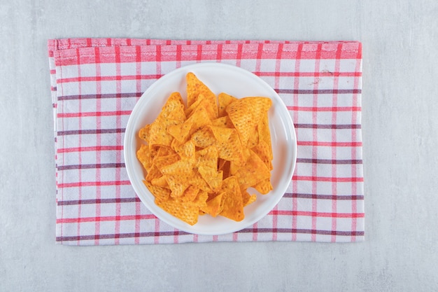 Foto gratuita chips de triángulo con especias en un plato blanco sobre piedra.