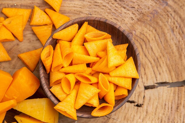 Chips de vista superior esparcidos de tazón de fuente de queso en la mesa de madera