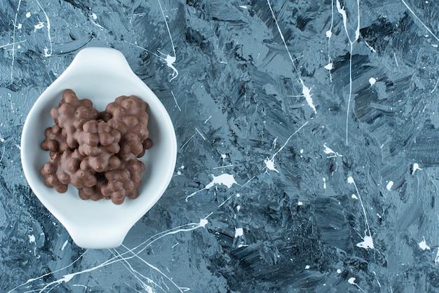 Chocolate con avellanas en un bol, sobre la mesa azul.