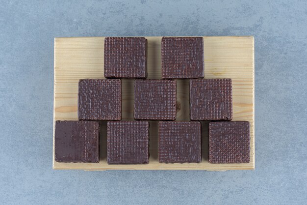 Chocolate bañado en barra de oblea crujiente en el tablero, en la mesa de mármol.