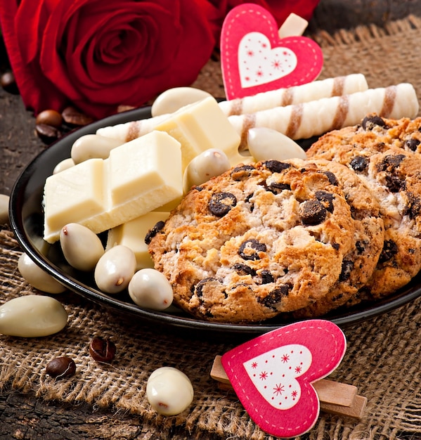 Chocolate blanco, almendras y galletas en una superficie de madera