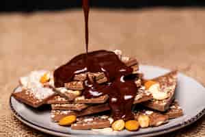 Foto gratuita chocolate caliente que vierte en los caramelos en cilicio blanco de la placa.