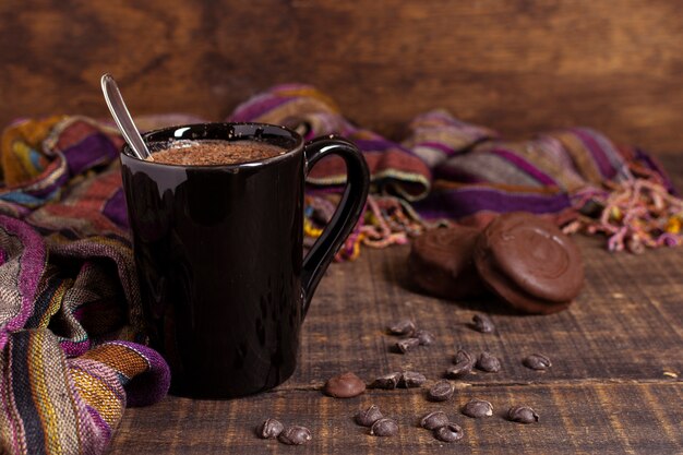 Chocolate caliente en taza con galletas y chips de cacao.