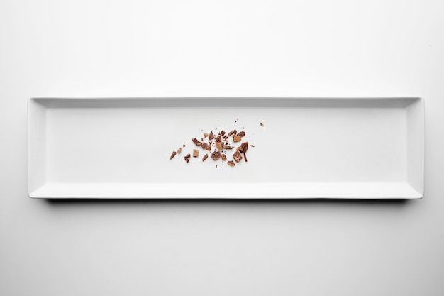 El chocolate se desmorona aislado en el centro de la placa de cerámica rectangular sobre fondo blanco de mesa