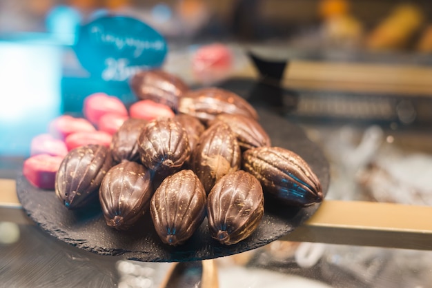 Chocolates con forma de fruta de cacao en bandeja de roca en el gabinete de vidrio