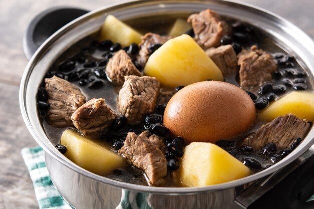 Cholent judío tradicional en cazuela sobre mesa de madera