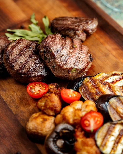 Foto gratuita chuleta de carne a la parrilla con berenjenas, champiñones, tomates y romero a bordo