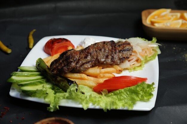 Chuletas de carne asada con patatas fritas y verduras