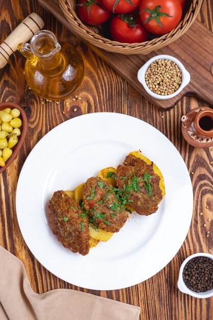 Chuletas de carne con papas especias verdes tomate vista superior