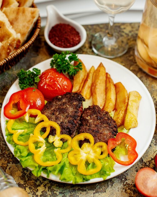 Chuletas de carne con papas fritas y verduras.