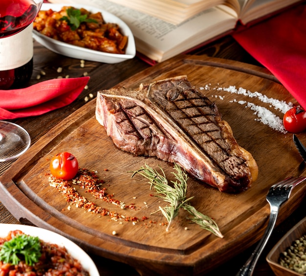 Foto gratuita chuletón de ternera servido en tabla de madera con listón de romero