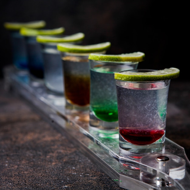 Foto gratuita chupitos de primer plano con bebidas de color y limón en un vaso