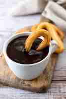 Foto gratuita churros tradicionales españoles con desayuno de chocolate caliente sobre mesa de madera