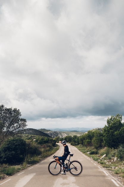 Ciclista en bicicleta al atardecer en una carretera de montaña