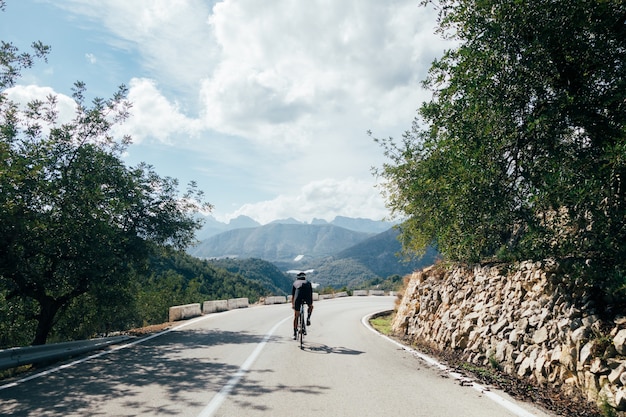 Ciclista en bicicleta al atardecer en una carretera de montaña