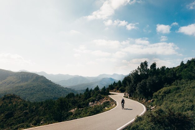 Ciclista en bicicleta al atardecer en una carretera de montaña