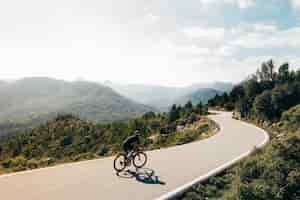 Foto gratuita ciclista en bicicleta al atardecer en una carretera de montaña