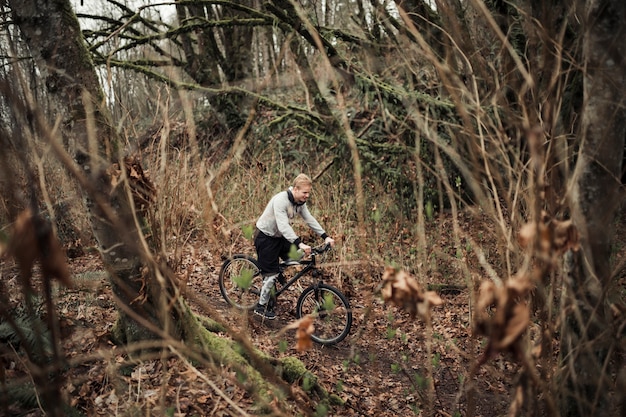 Ciclista masculino cabalgando en el bosque