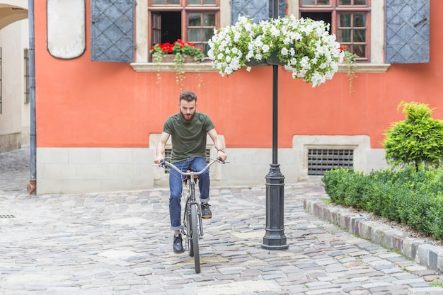 Ciclista masculino joven que monta el pavimento empedrado del guijarro de la bicicleta