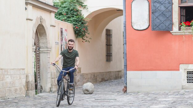 Ciclista masculino montando bicicleta en el pavimento de piedra