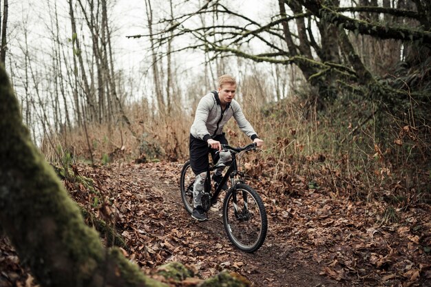 Ciclista de montaña montando en bicicleta deportiva en la pista forestal