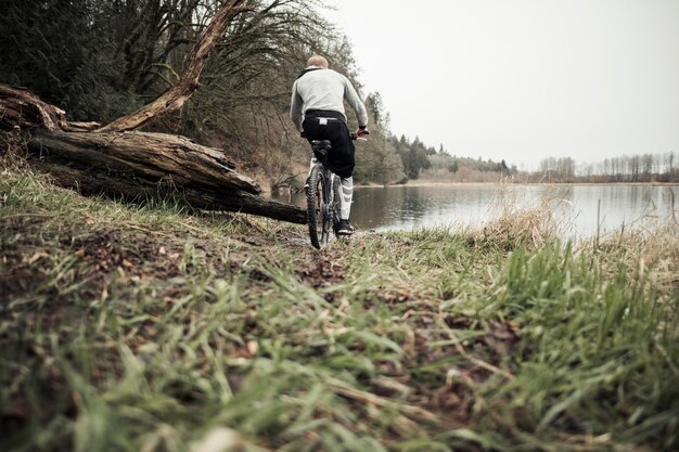 Ciclista montando bicicleta de montaña hacia el lago