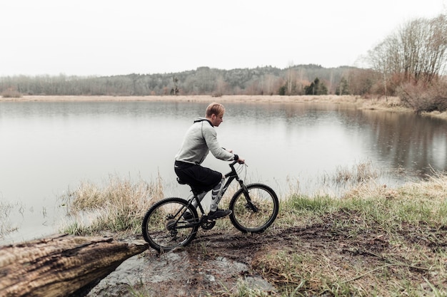 Ciclista montando su bicicleta de montaña cerca del lago idílico