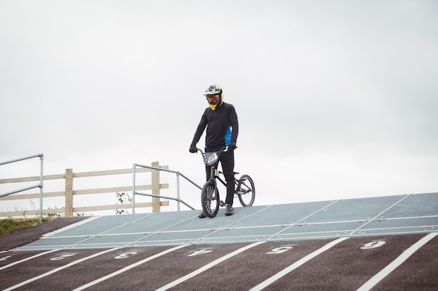 Foto gratuita ciclista de pie con bicicleta bmx en la rampa de inicio