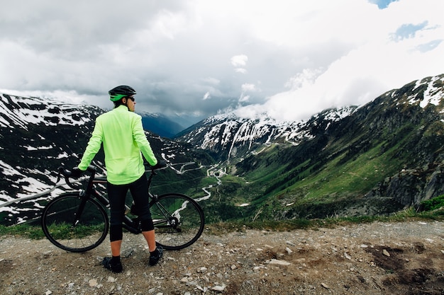 Foto gratuita ciclista de pie con bicicletas de carretera en el fondo del hermoso paisaje de montañas alpinas