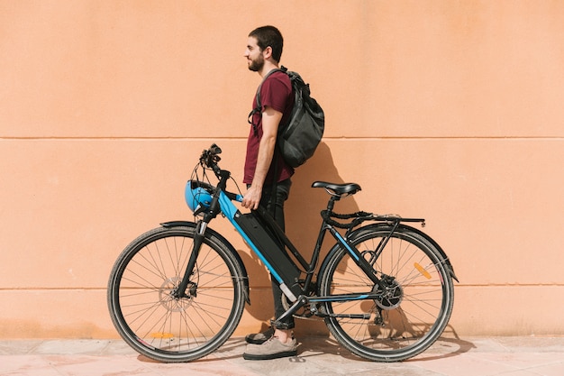 Ciclista urbano de pie junto a la bicicleta eléctrica.