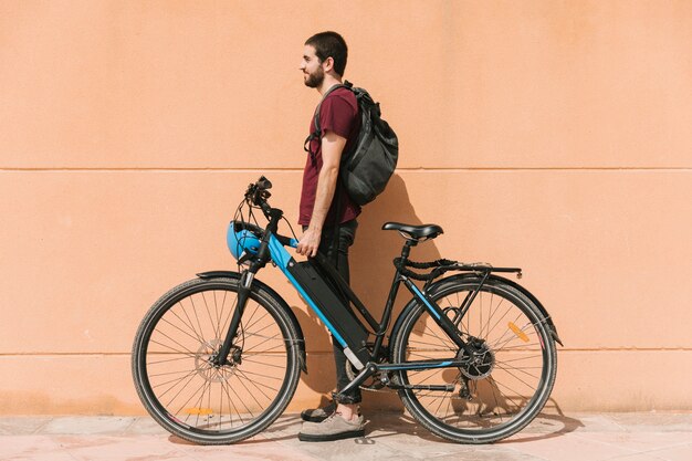 Ciclista urbano de pie junto a la bicicleta eléctrica.