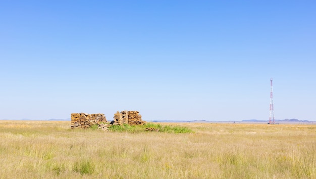 Cielo despejado sobre un prado seco desierto con antiguas ruinas de edificios de piedra en Sudáfrica