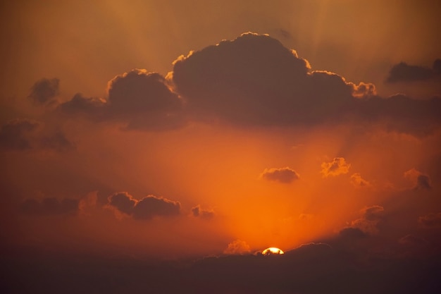 Cielo naranja con nubes y sol