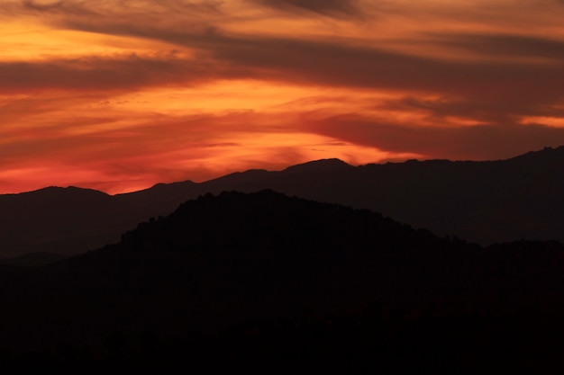 Cielo nublado amarillo oscuro con montañas negras